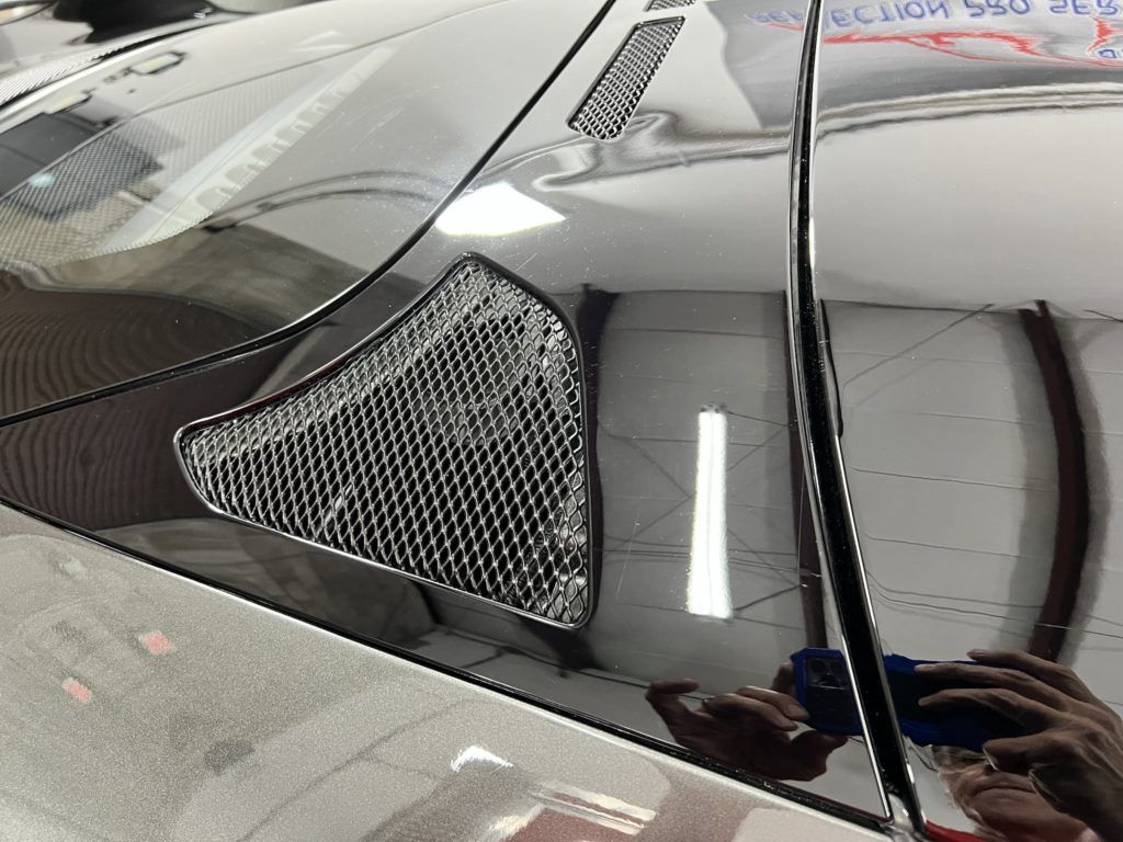 A person is taking a picture of the hood of a car.