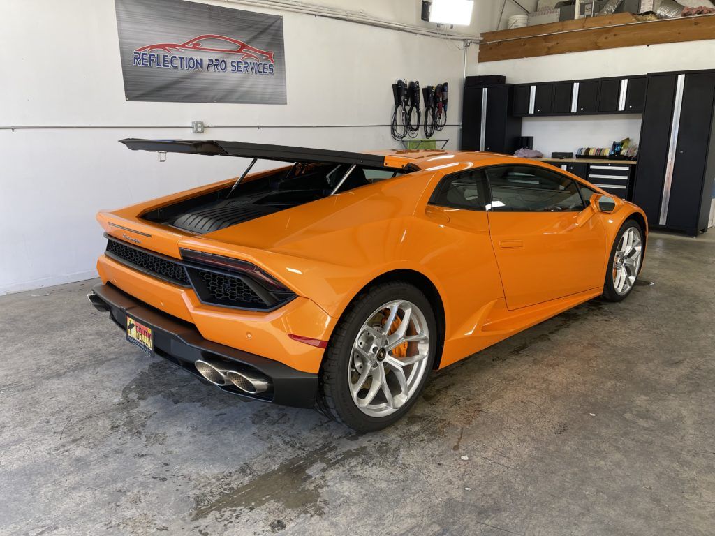 A lamborghini huracan is parked in a garage with the trunk open.
