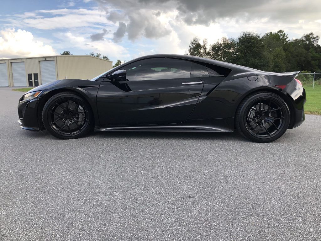 A black sports car is parked on the side of the road.