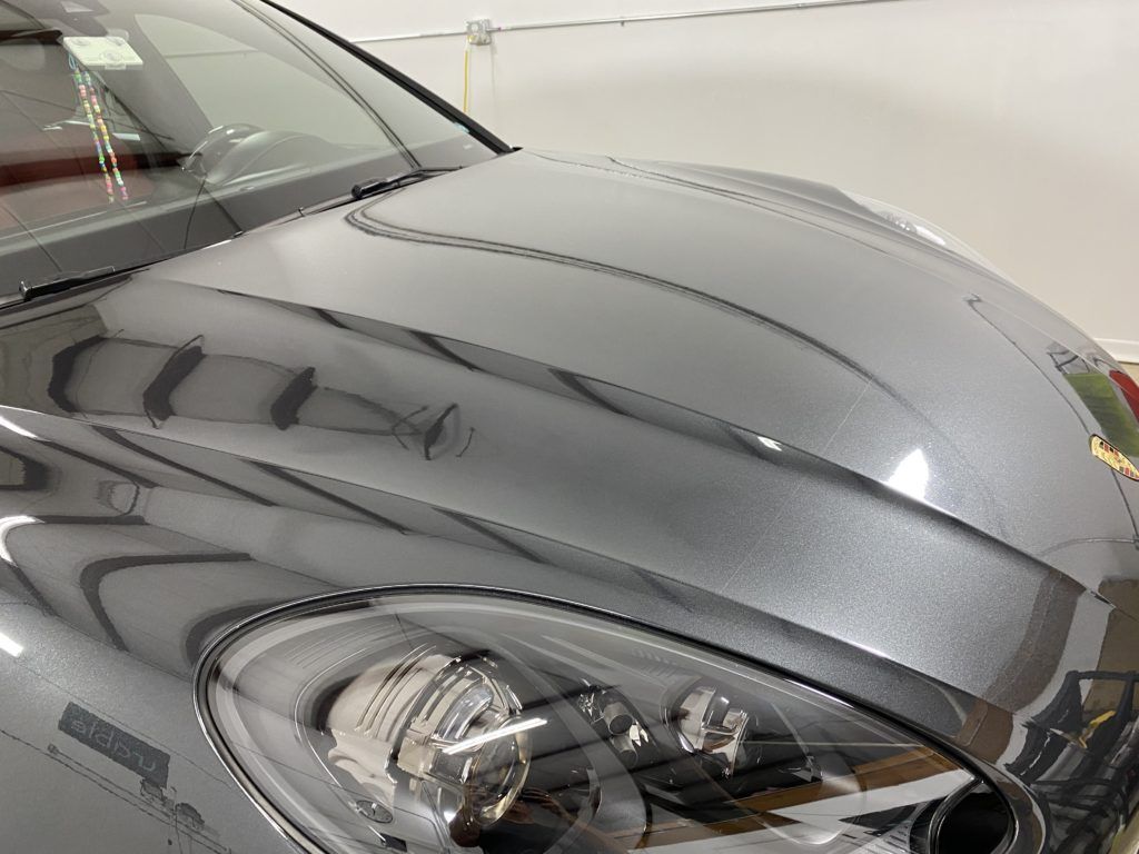 A close up of a car 's hood and headlights in a garage.