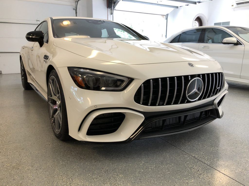 A white mercedes benz is parked in a garage.
