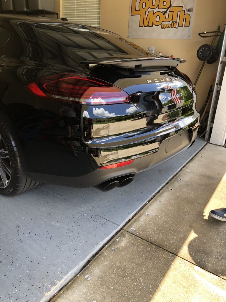 A black car is parked in a garage with a sign on the wall.
