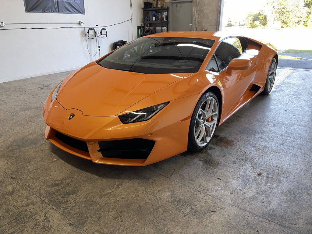 An orange lamborghini huracan is parked in a garage.