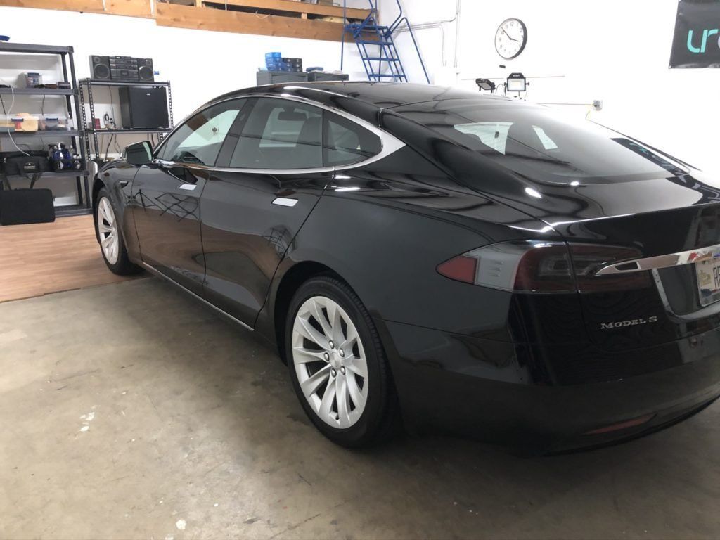 A black tesla model s is parked in a garage.