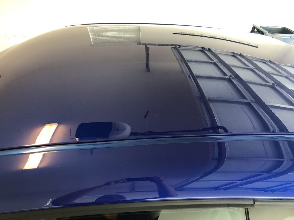 A blue car hood is reflected in a garage door