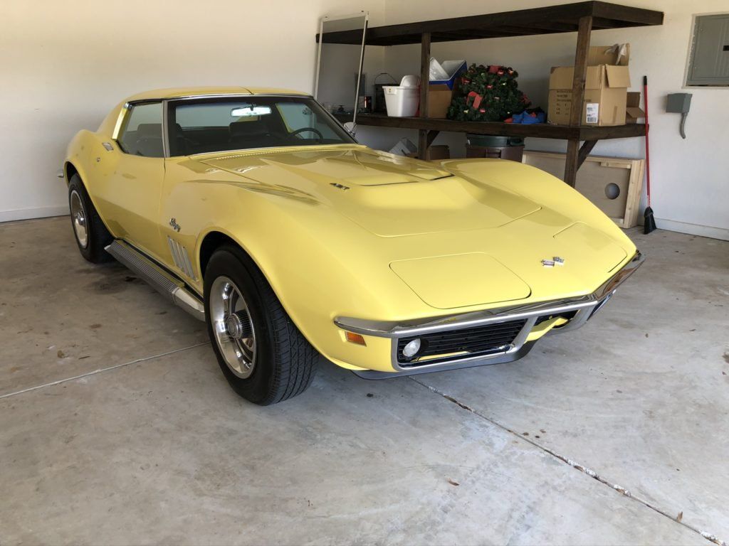 A yellow corvette is parked in a garage.