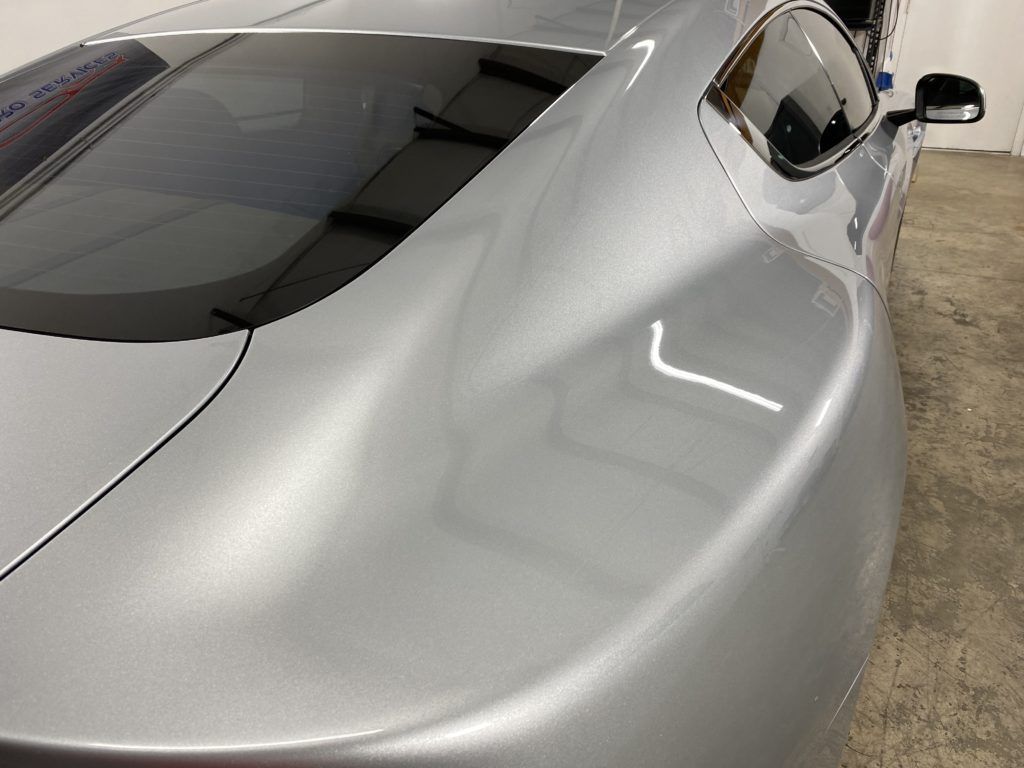 A silver sports car is parked in a garage.