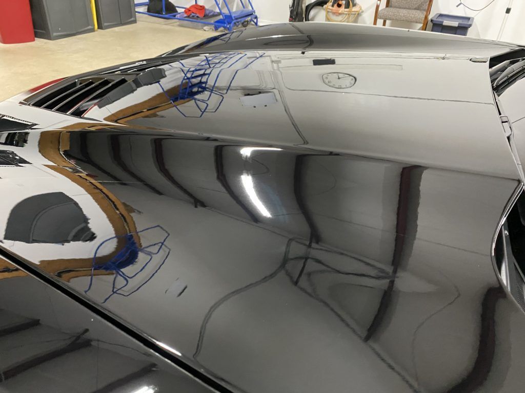 A close up of the hood of a black car in a garage.