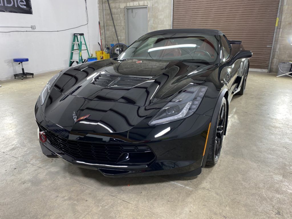 A black sports car is parked in a garage.