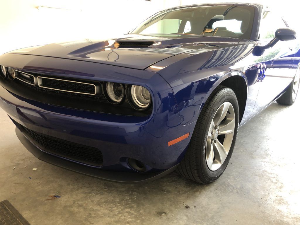 A blue dodge challenger is parked in a garage.