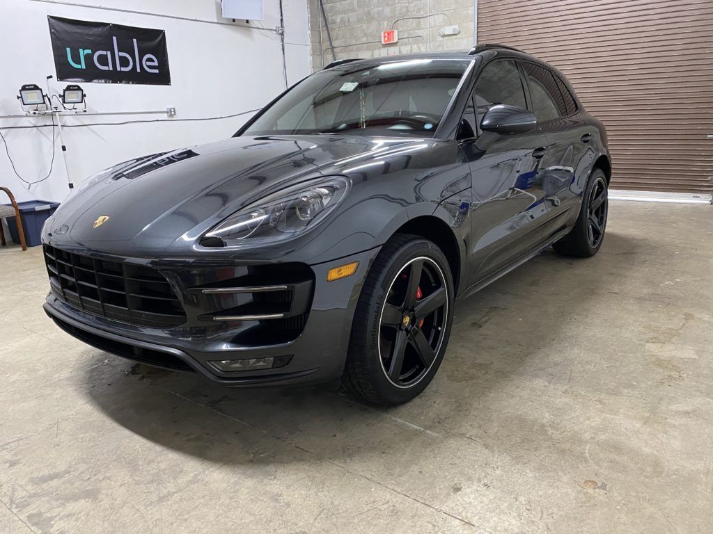 A gray porsche macan turbo is parked in a garage.