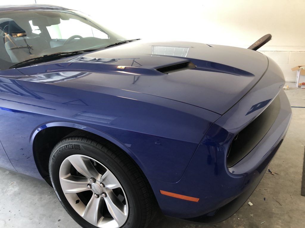 A blue dodge challenger is parked in a garage.