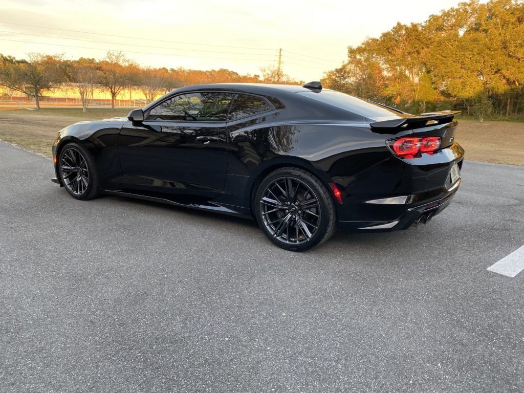 A black chevrolet camaro is parked in a parking lot.