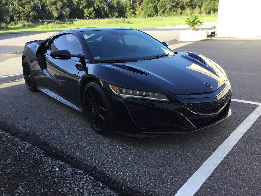A black sports car is parked in a parking lot