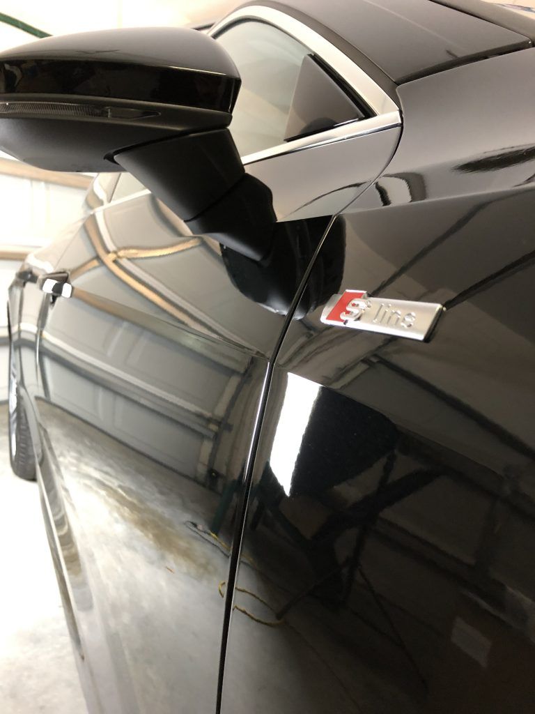 A close up of a car 's side mirror and emblem in a garage.