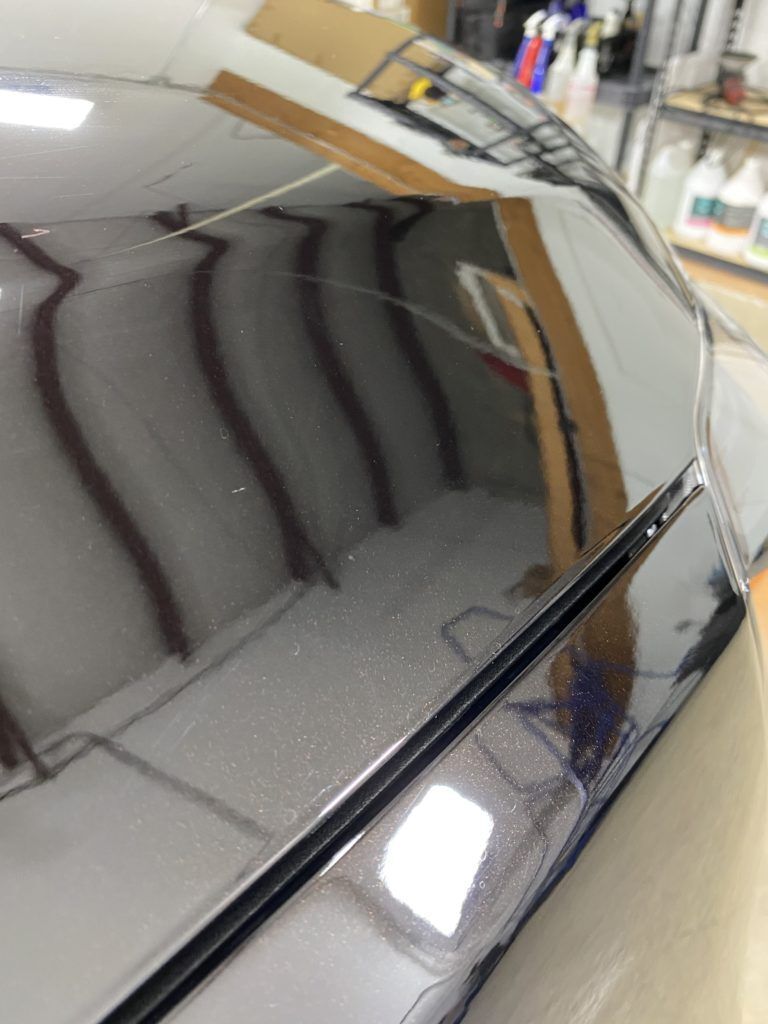 A close up of a car 's hood in a garage.