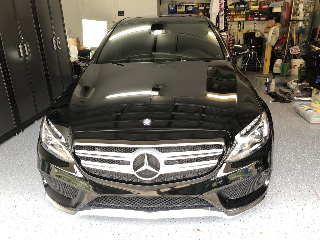 A black mercedes benz is parked in a garage.