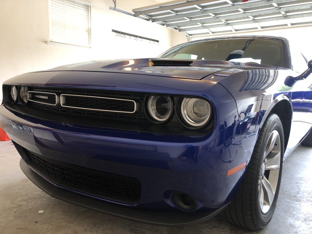 A blue dodge challenger is parked in a garage.