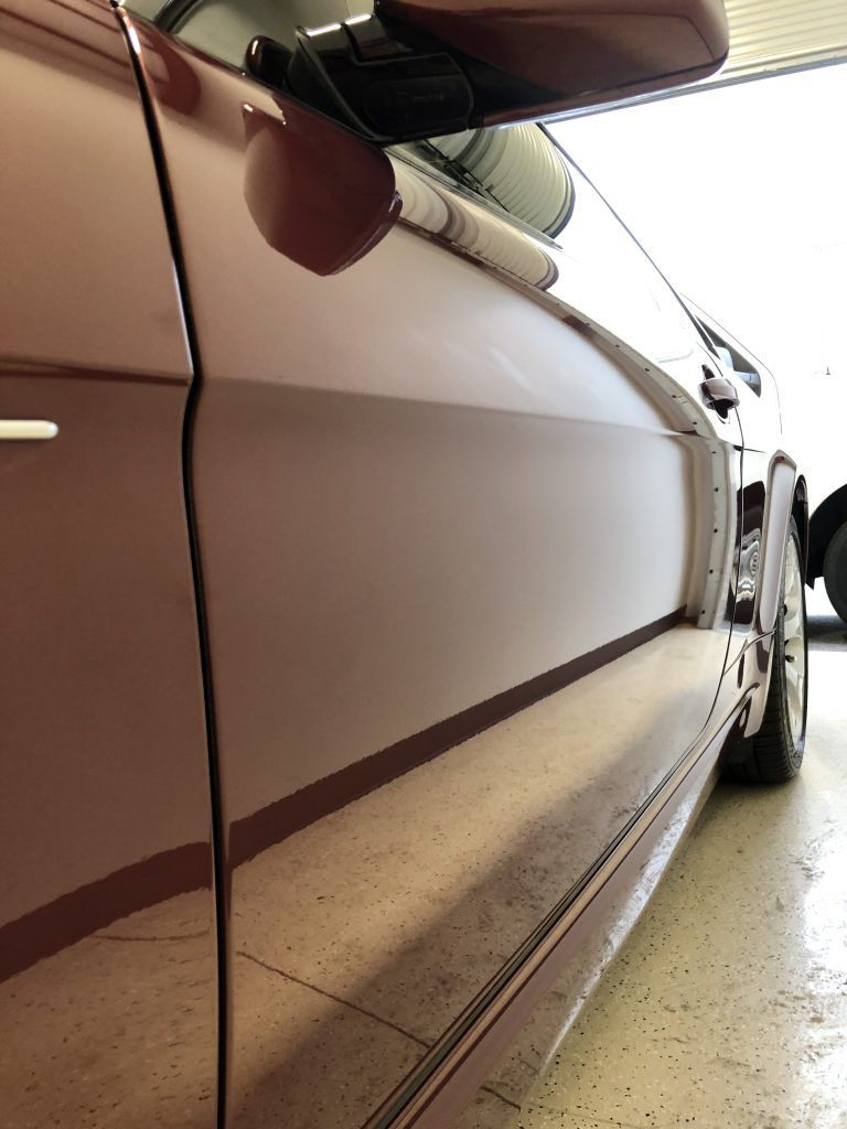 A car is parked in a garage with the door open