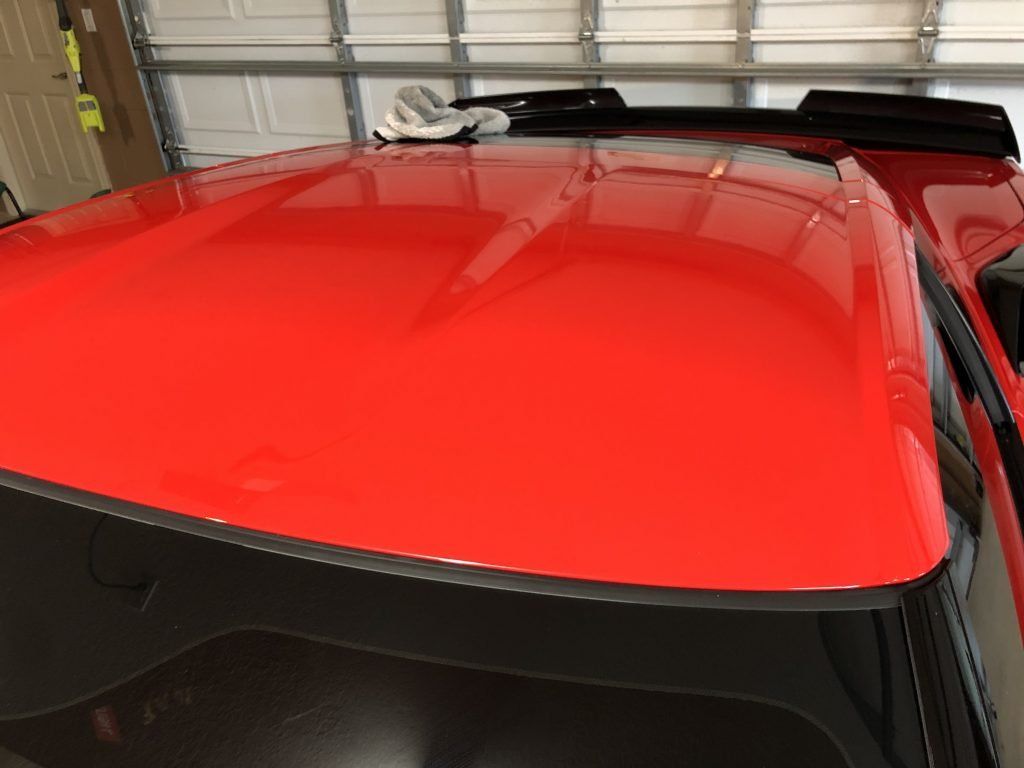 The roof of a red car is sitting in a garage.