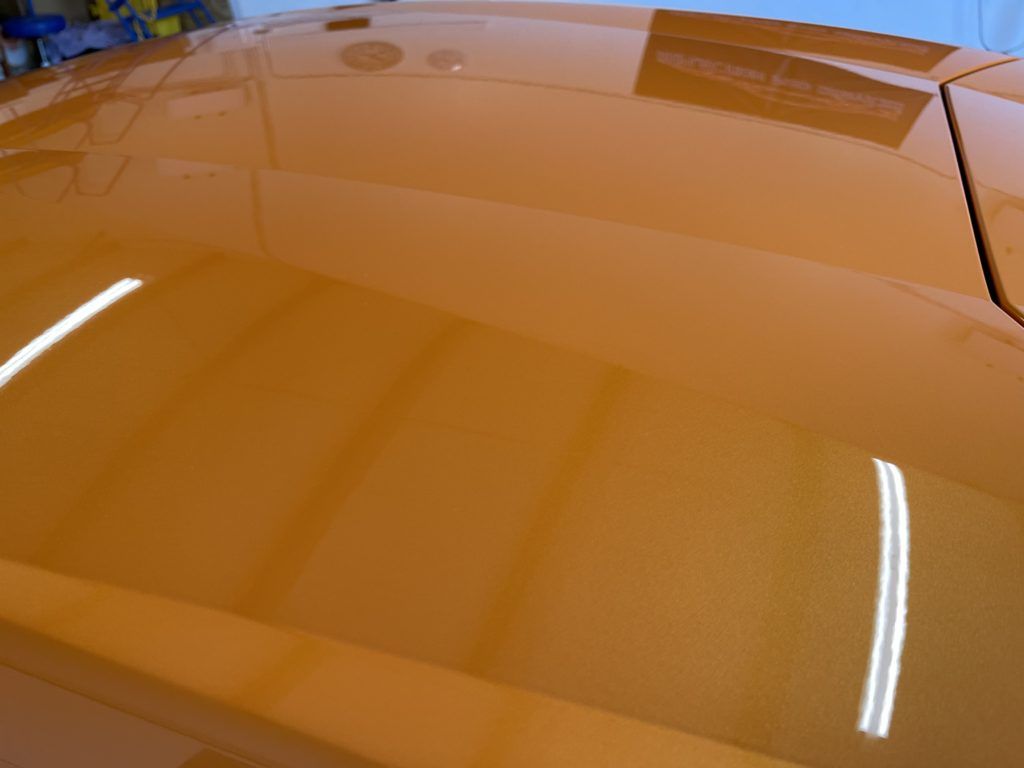 A close up of the hood of an orange car