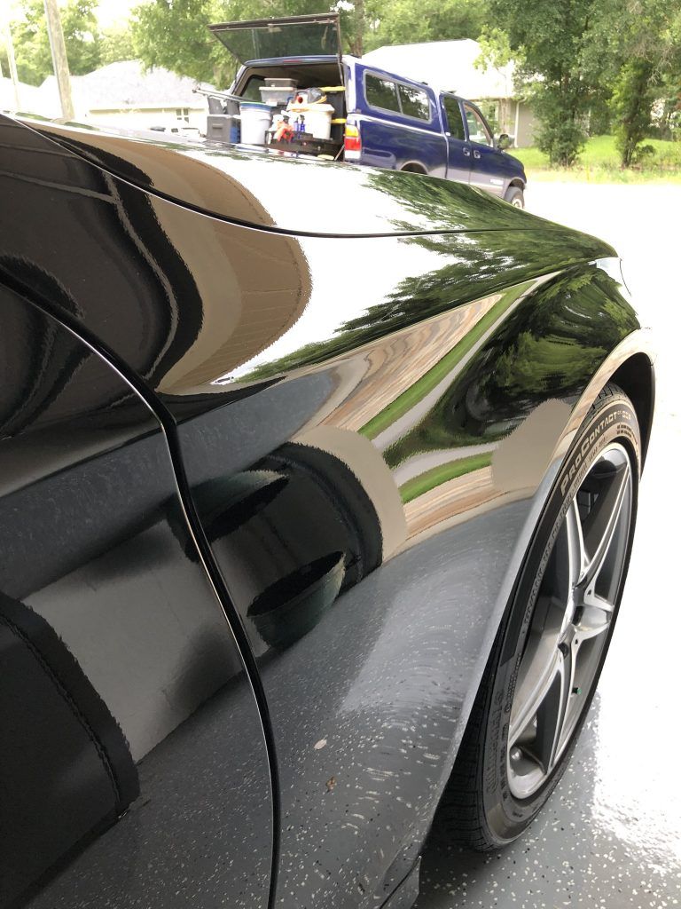 A black car is parked in a garage with the trunk open.