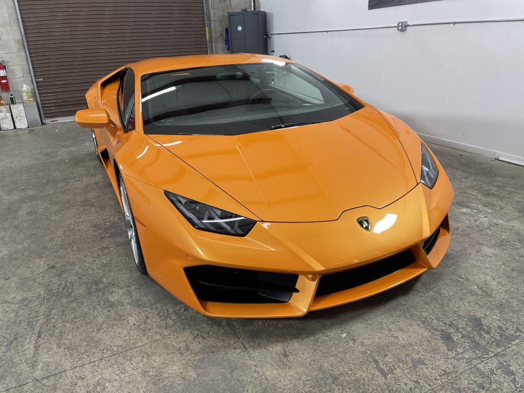 An orange lamborghini huracan is parked in a garage.