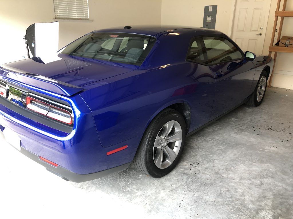 A blue dodge challenger is parked in a garage.