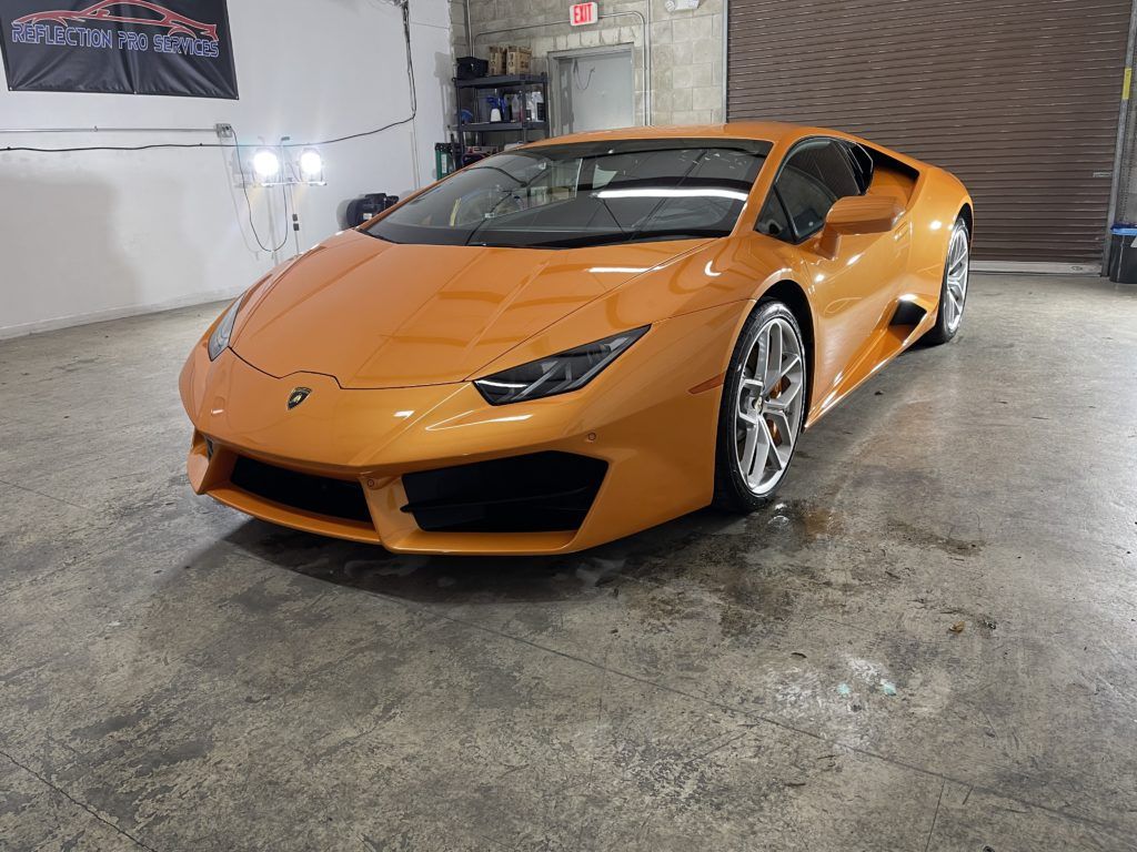 An orange lamborghini huracan is parked in a garage.