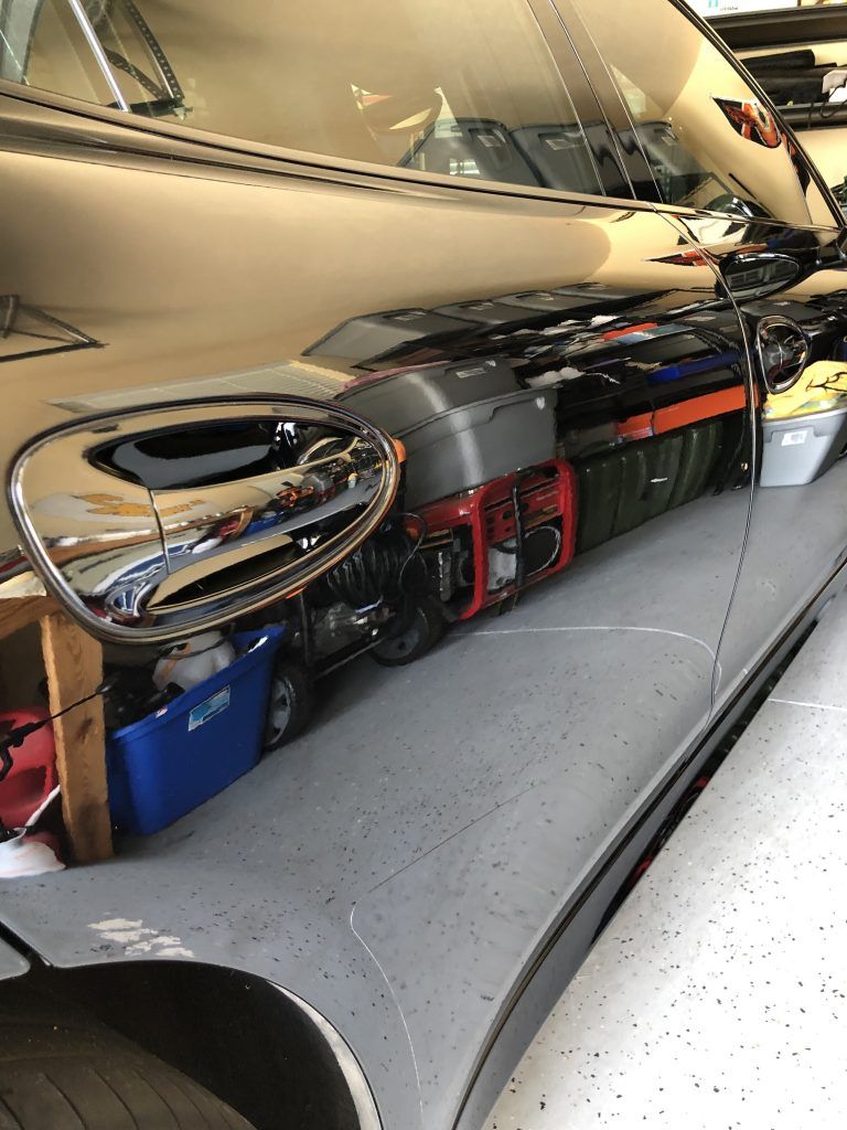 A car is parked in a garage next to a row of generators.