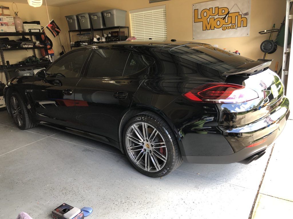 A black car is parked in a garage next to a sign that says loud health.