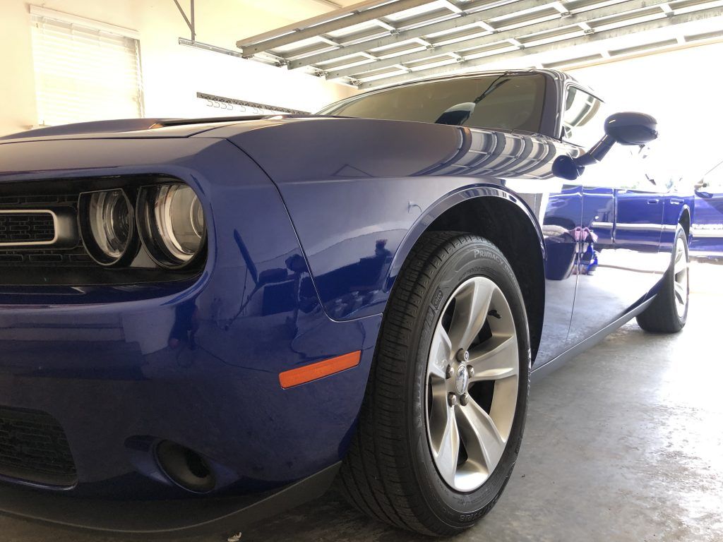 A blue dodge challenger is parked in a garage.