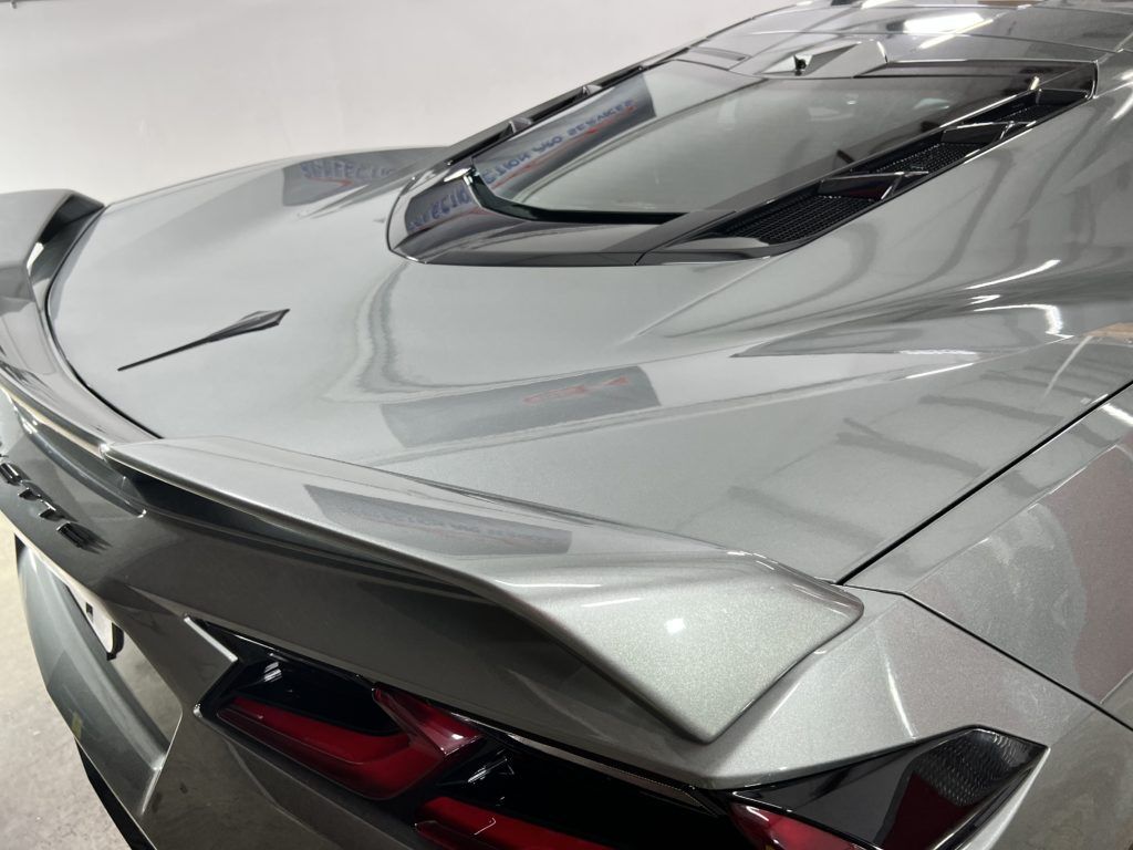 A silver sports car with a spoiler on the back is parked in a garage.