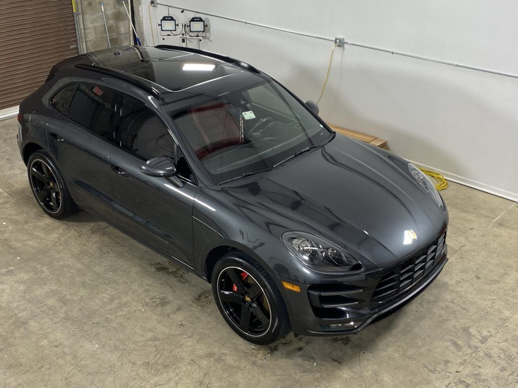 A gray porsche macan turbo is parked in a garage.