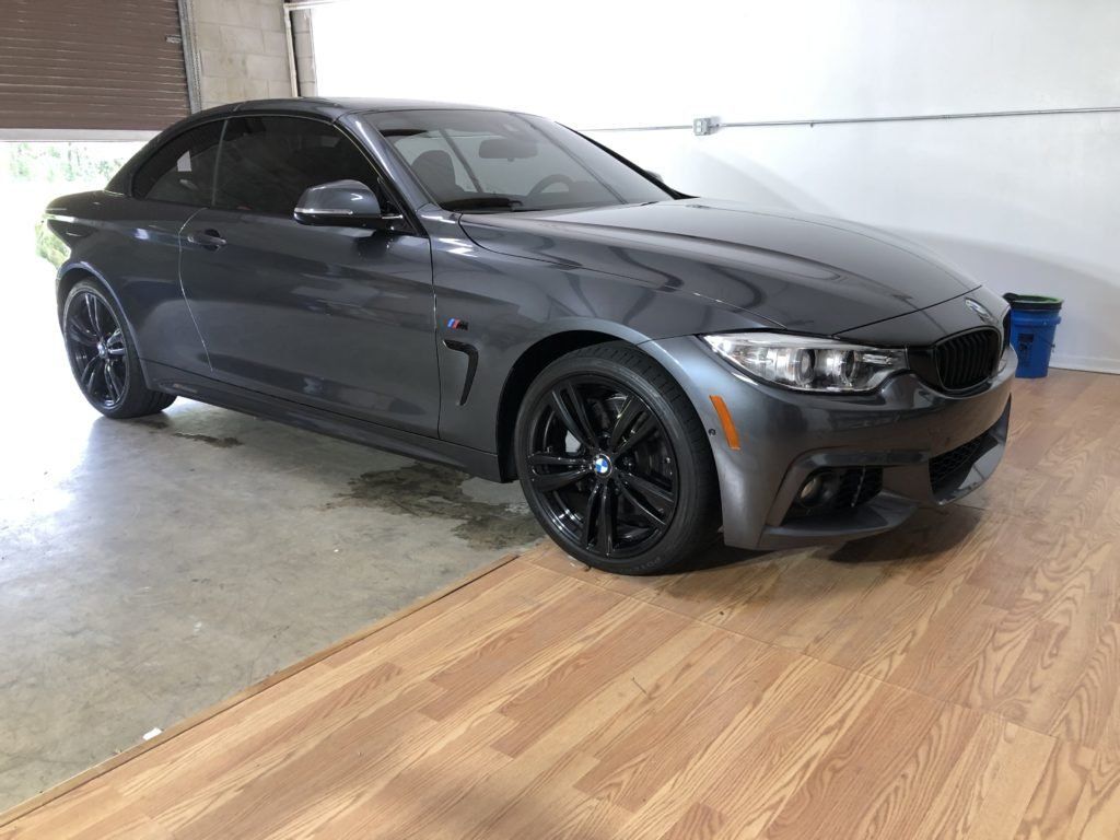 A bmw m3 is parked in a garage next to a wooden floor.