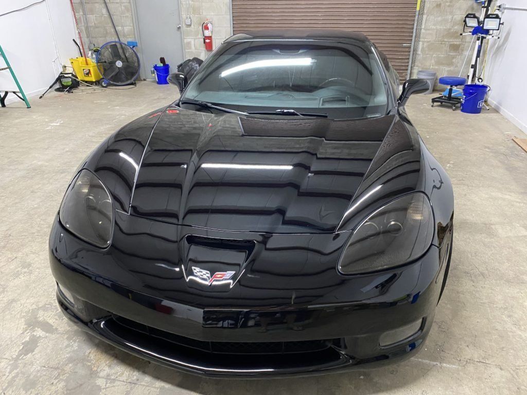 A black sports car is parked in a garage.