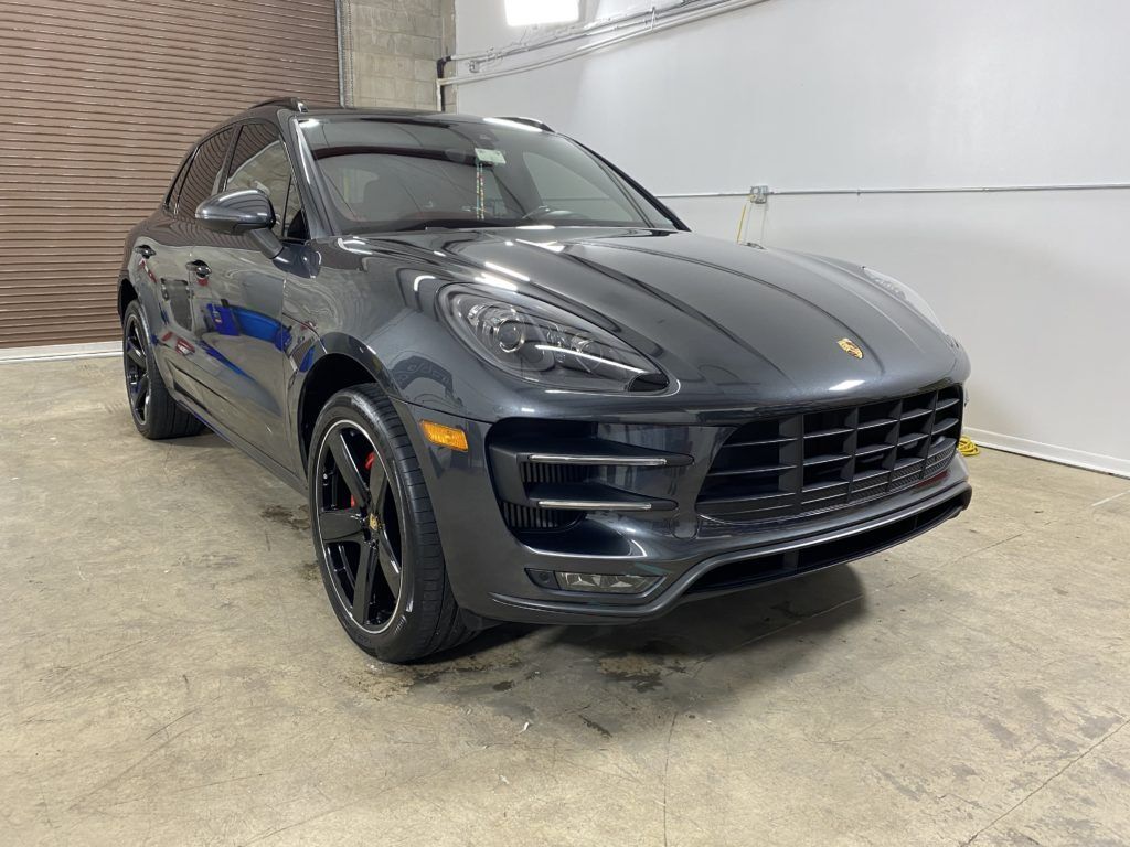 A gray porsche macan turbo is parked in a garage.