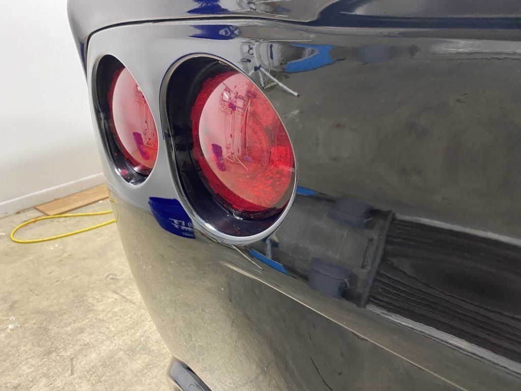 A black car with red tail lights is parked in a garage.