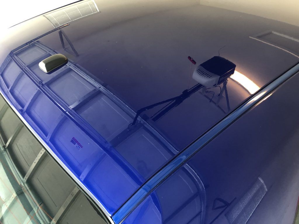 A blue car is parked in a garage with a garage door open