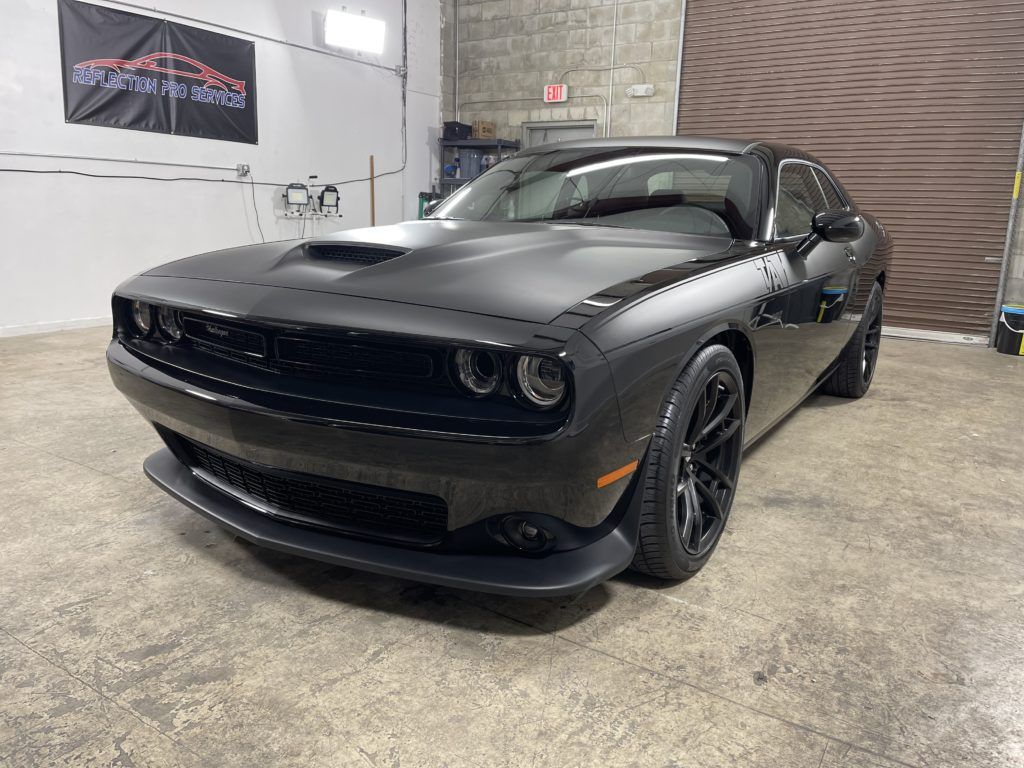 A black dodge challenger is parked in a garage.