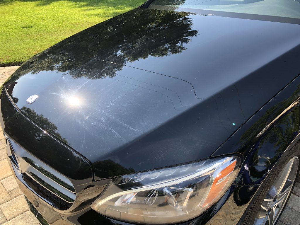 A close up of a black car 's hood and headlights.