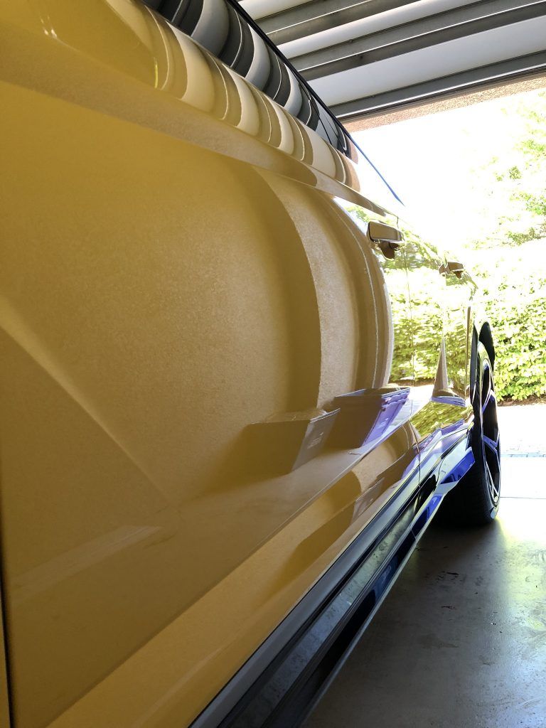 A yellow and blue car is parked in a garage