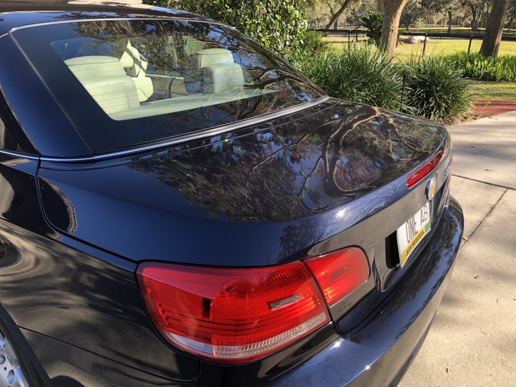 The back of a black car is parked on the side of the road.