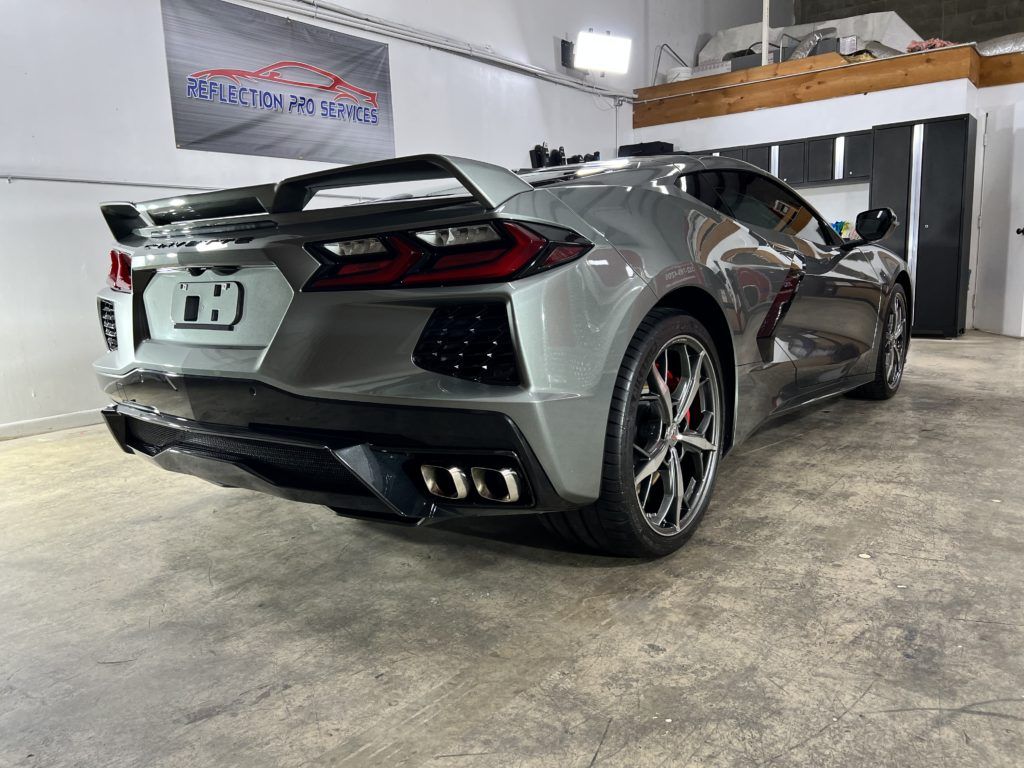 A silver corvette is parked in a garage.