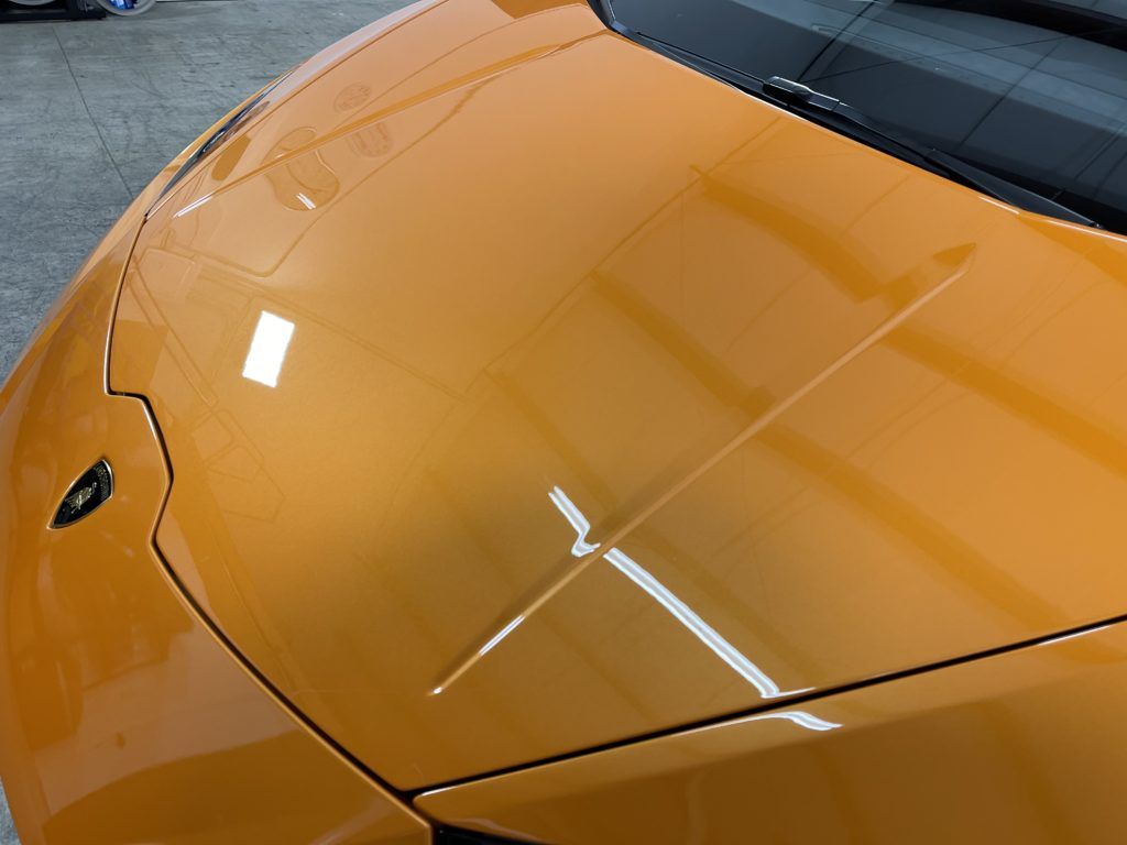 A close up of the hood of an orange sports car