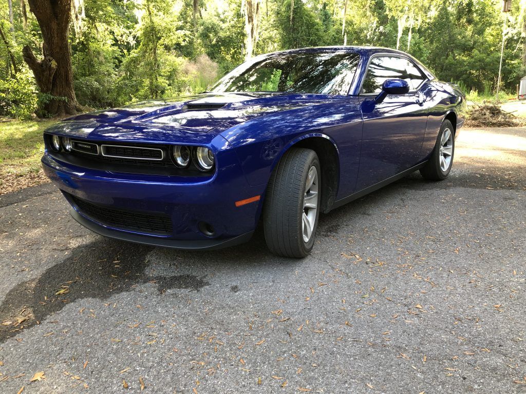 A blue dodge challenger is parked on the side of the road.