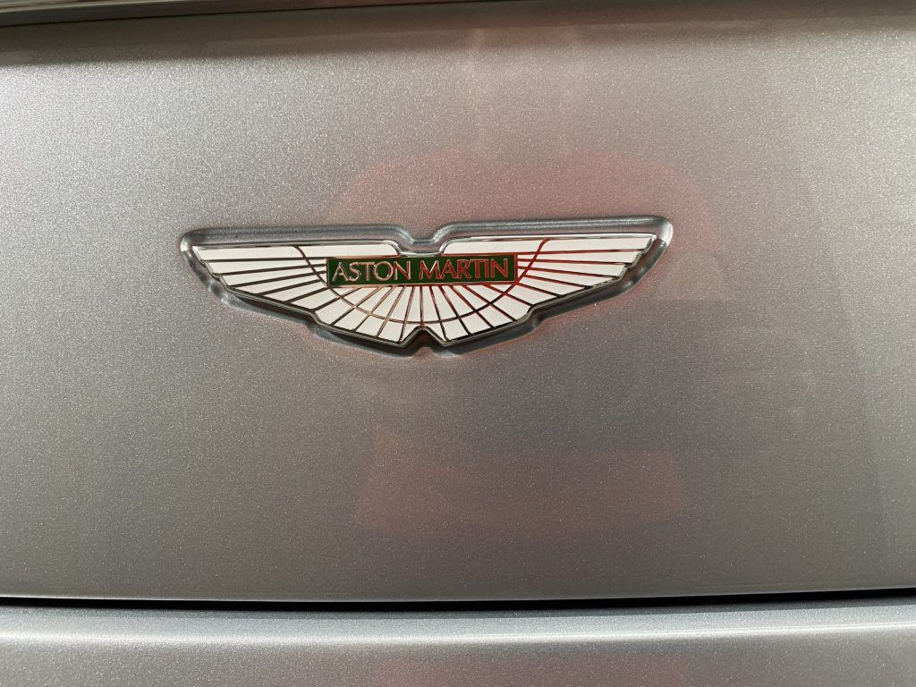 The emblem on the back of a silver aston martin car.