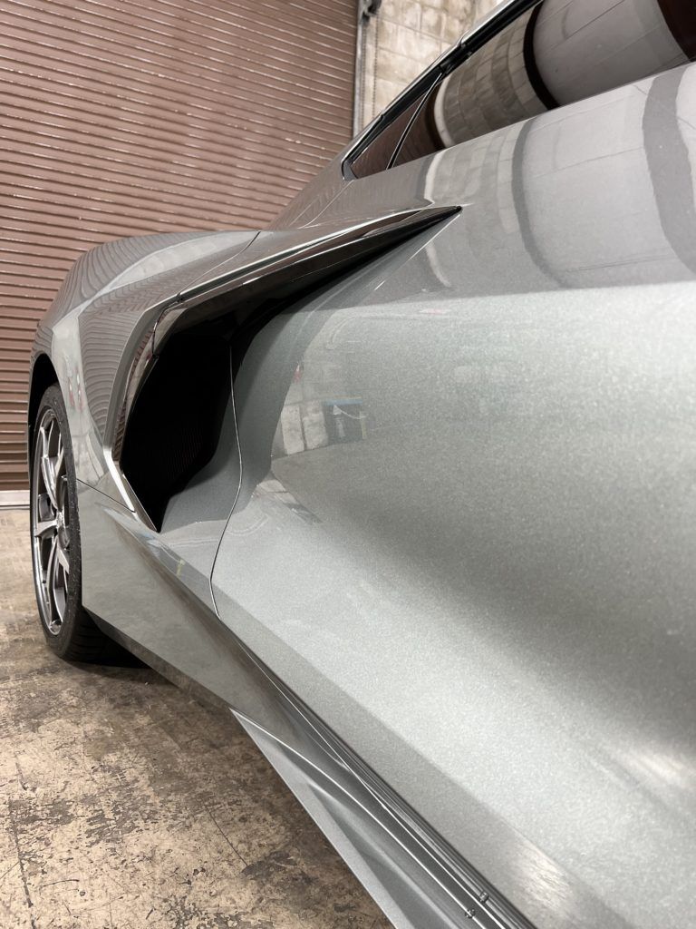 A close up of a silver sports car parked in a garage.