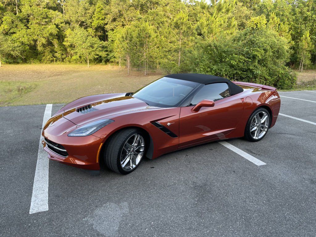 A red corvette convertible is parked in a parking lot.