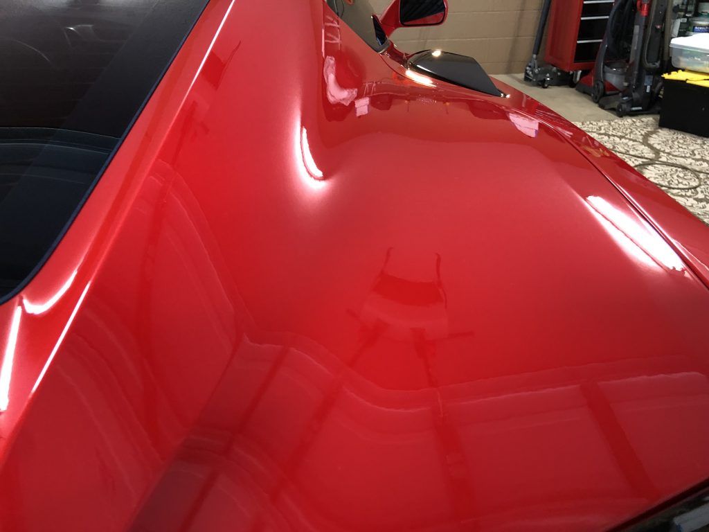A close up of a red car hood in a garage